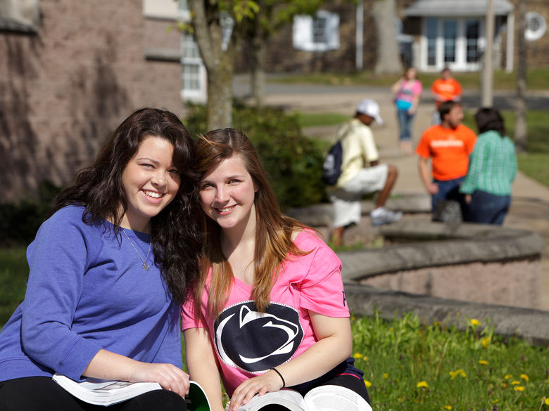 Two female students studying together outside in the sunshine